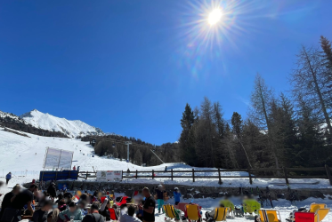 persone che prendono il sole nel dehor di un locale situato sulle piste da sci di Pila , alberi, cielo azzurro e sole