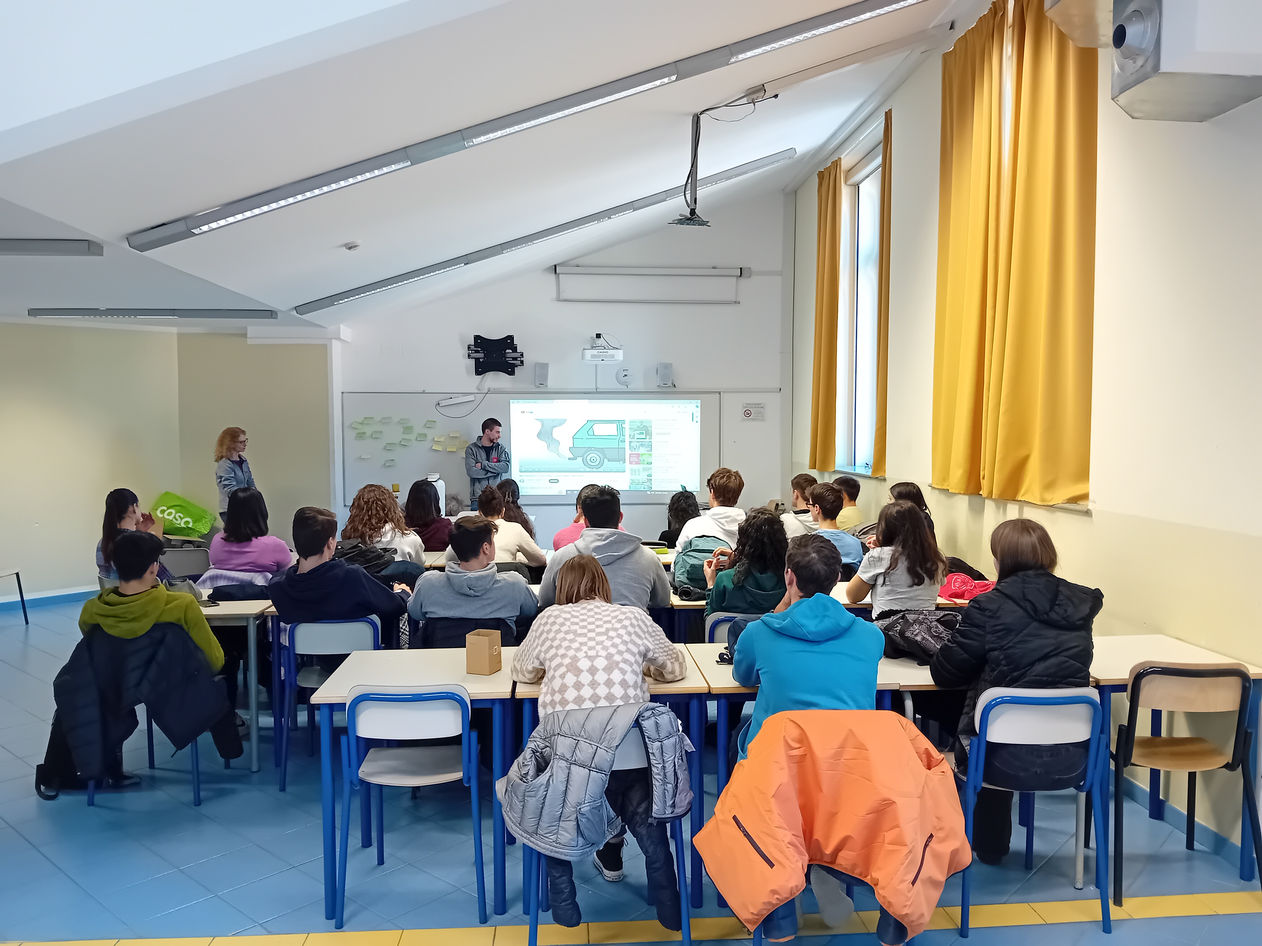 ragazzi e ragazze di una classe del liceo che ascoltano un momento di spiegazione da parte di un collega di arpa