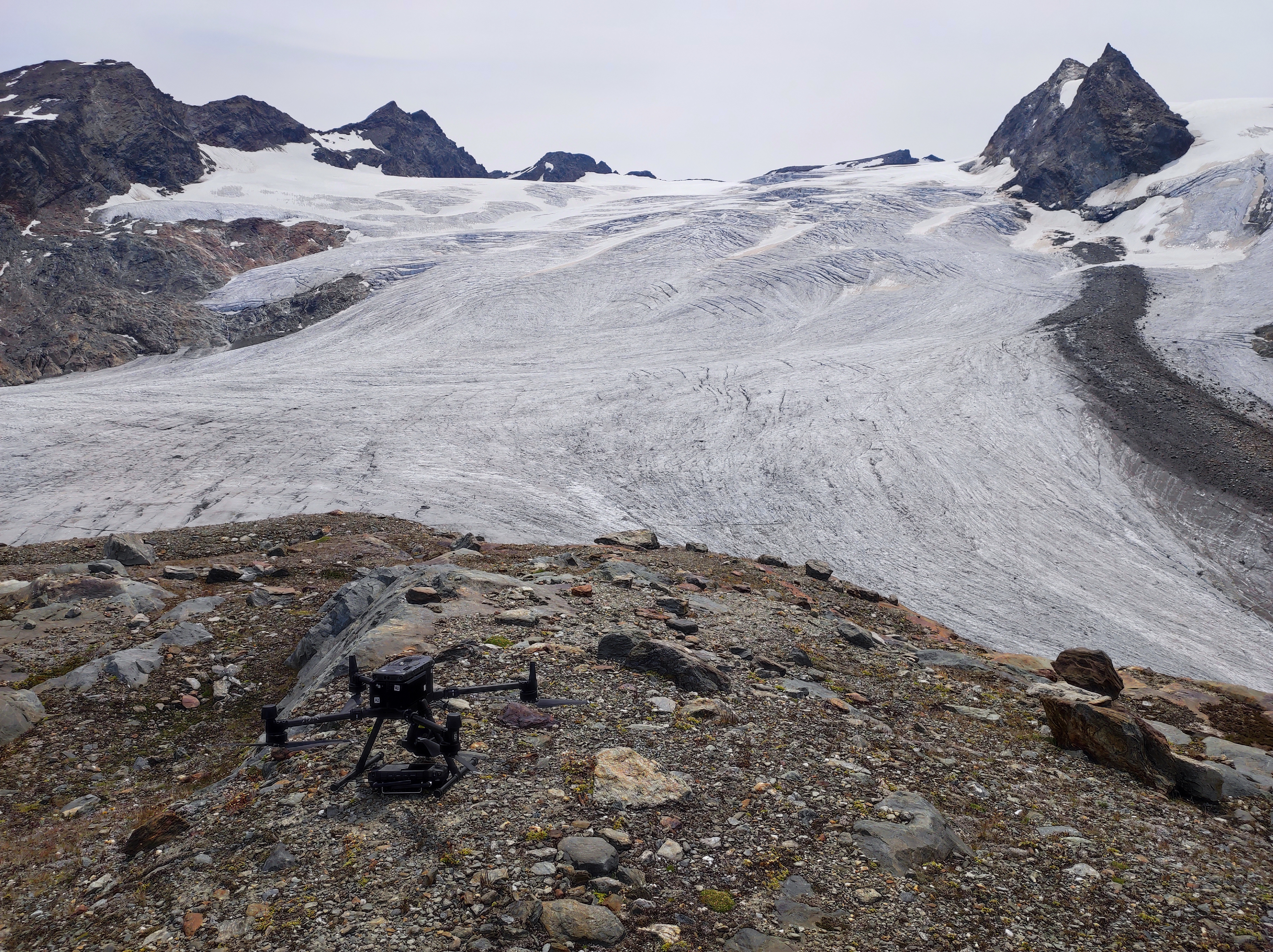 fronte del ghiaccio del rutor e in primo piano un drone appoggiato sulle rocce
