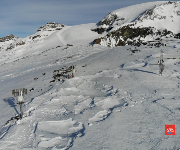 pianoro ricoperto di neve sul quale si vedono gli strumenti di arpa valle d'aosta di monitoraggio della neve