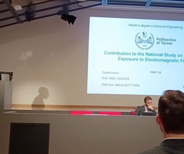 Edoardo Lagorio che inizia la discussione di tesi sullo scranno, mentre la stessa è proiettata sul muro a favore del pubblico. Di schiena il collega Danilo Amerio