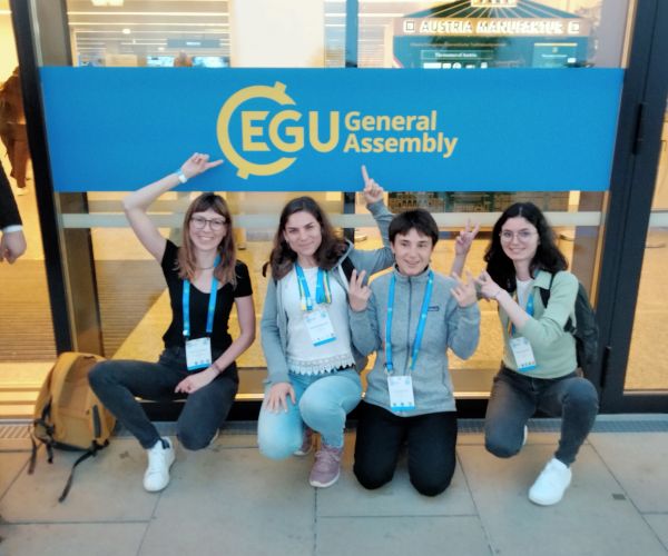 quattro ragazze accovacciate che indicano l'insegna EGU General Assembly