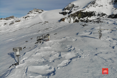 pianoro ricoperto di neve sul quale si vedono gli strumenti di arpa valle d'aosta di monitoraggio della neve