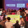 ragazzi e ragazze, esperti, docenti che si confrontano davanti a diversi poster in una sala conferenze