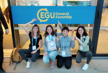 quattro ragazze accovacciate che indicano l'insegna EGU General Assembly