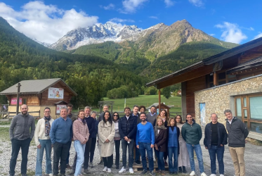 uomini e donne, partners del progetto, in piedi in primo piano, sullo sfondo la montagna e il cielo