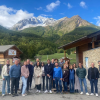 uomini e donne, partners del progetto, in piedi in primo piano, sullo sfondo la montagna e il cielo