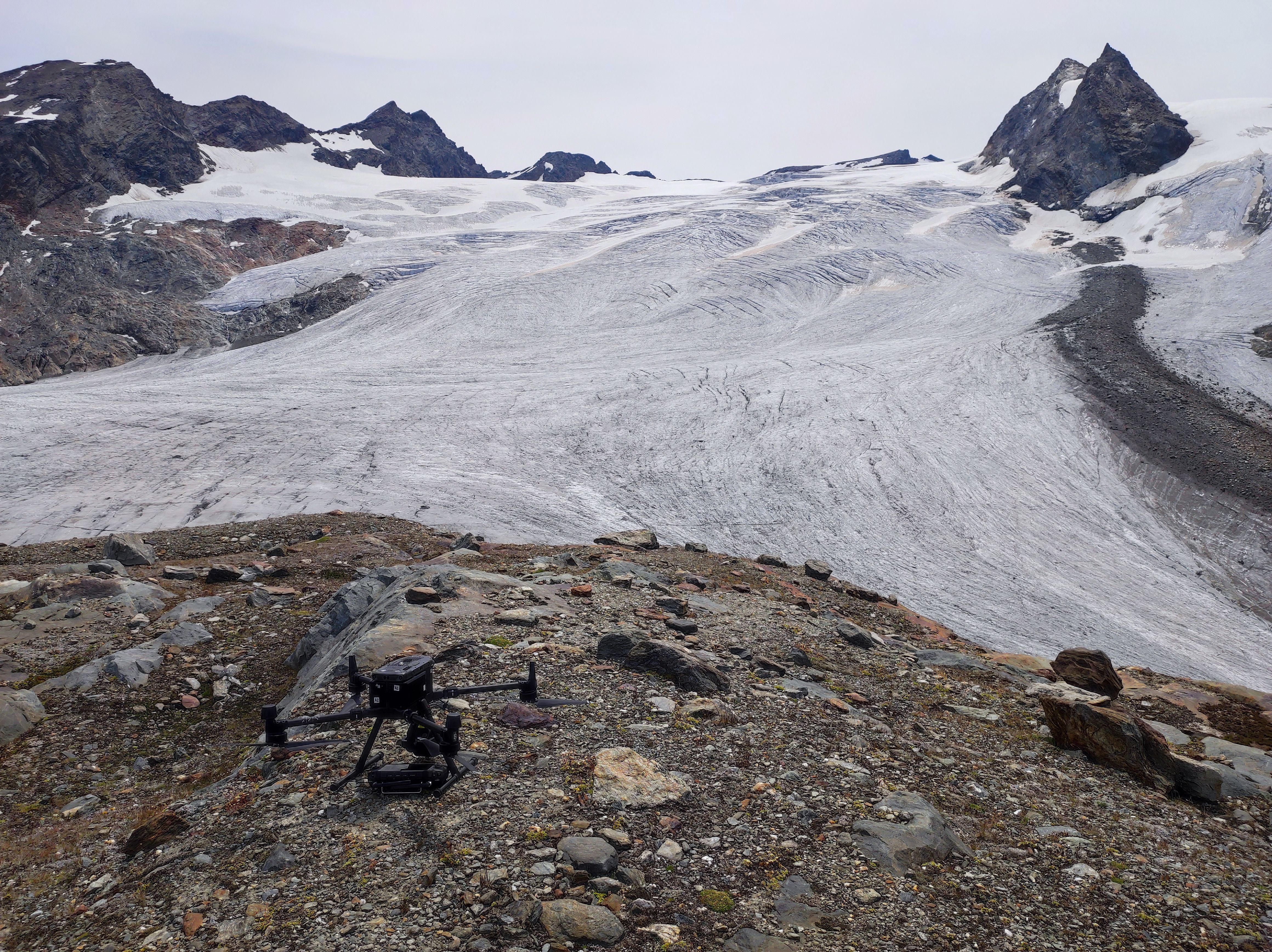 fronte del ghiaccio del rutor e in primo piano un drone appoggiato sulle rocce