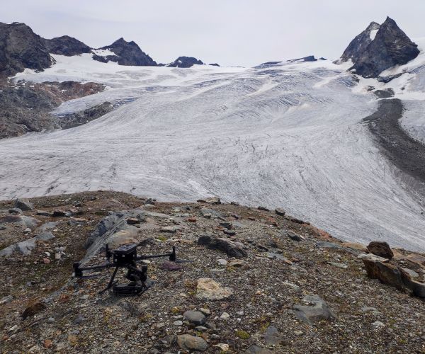 fronte del ghiaccio del rutor e in primo piano un drone appoggiato sulle rocce